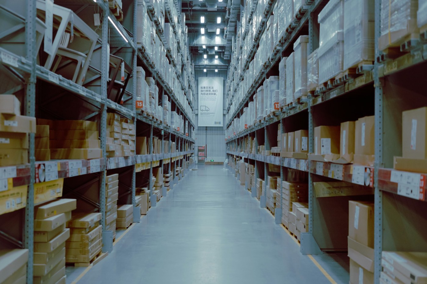 View down a warehouse aisle lined with tall racks of boxes